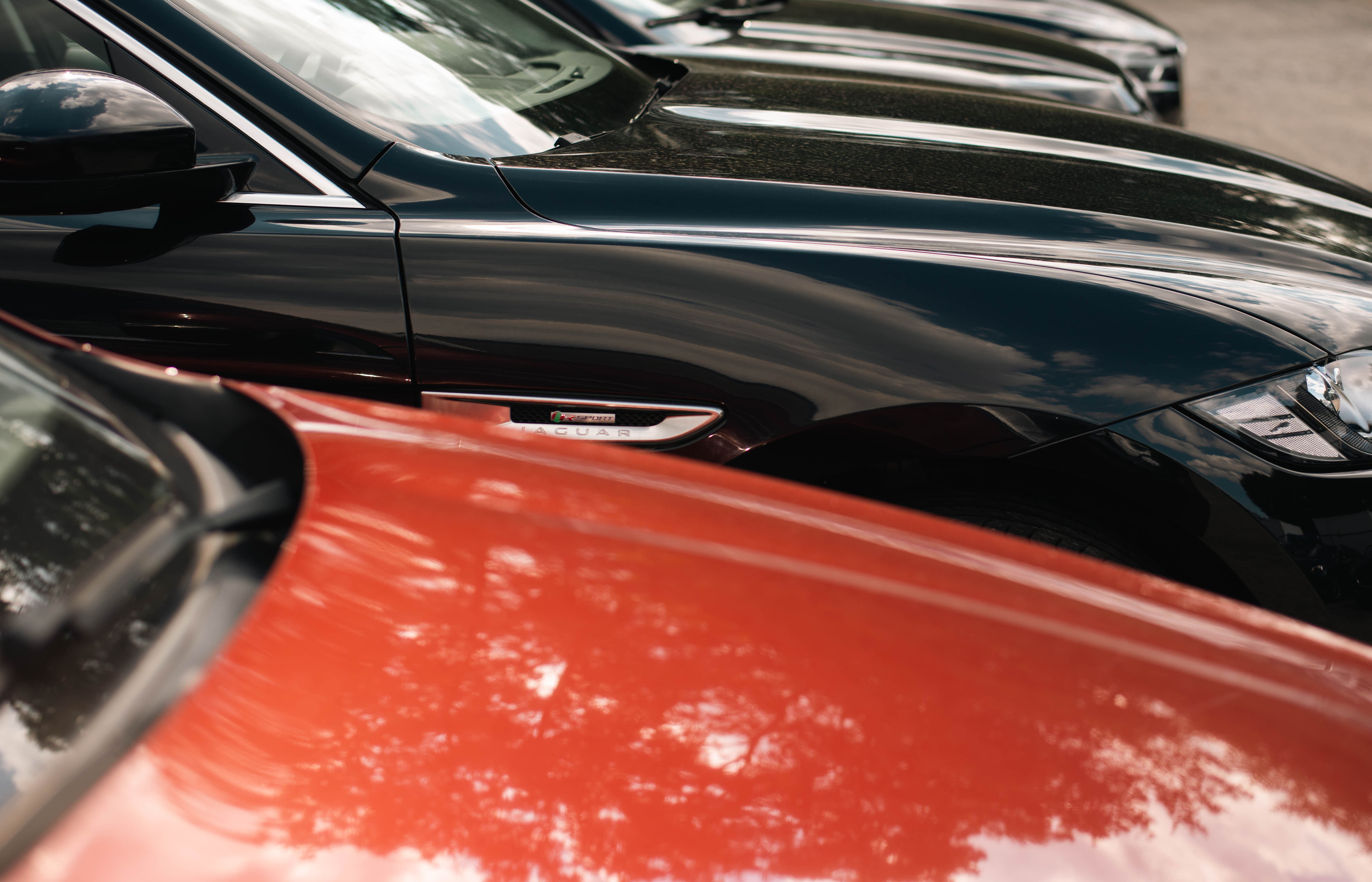 krupni plan crvenog automobila i crnog Jaguara parkiranog na parkiralištu eCarsTrade