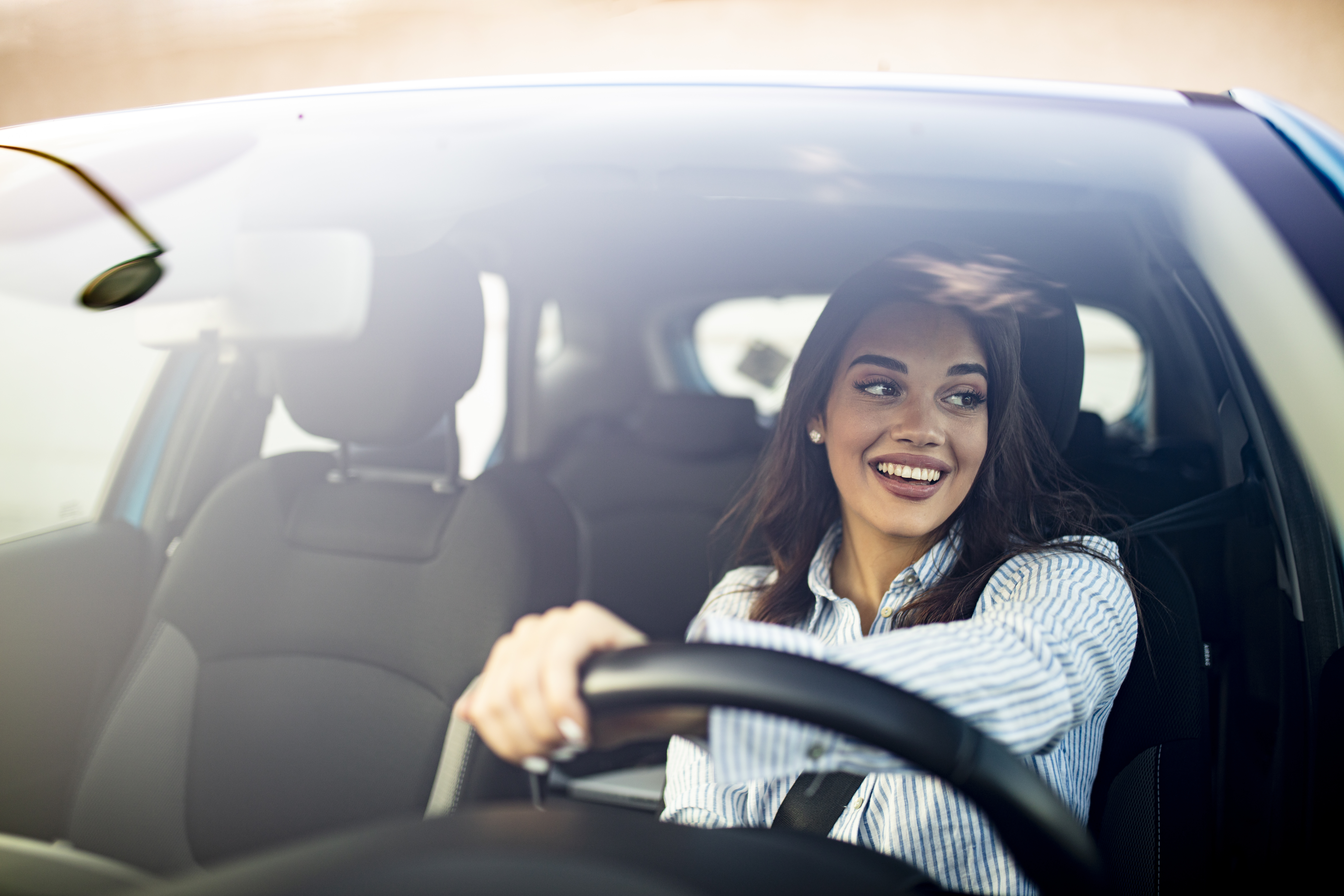 a woman smiling behind the wheel of a used car